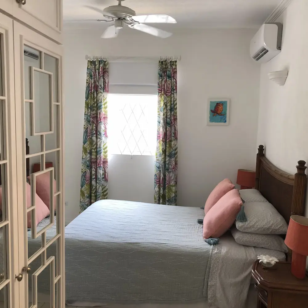 Air-conditioned bedroom at 7 Springcourt with queen-sized bed, tropical curtains and ceiling fan.