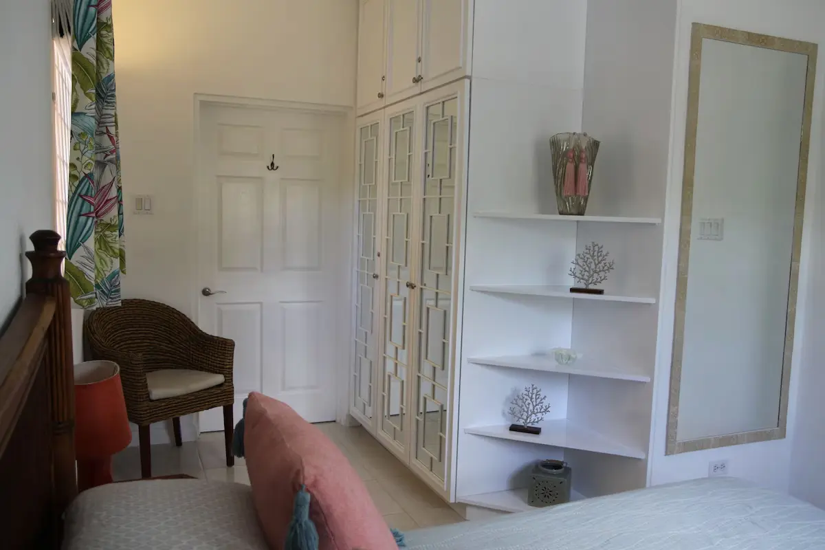 Bedroom detail at 7 Springcourt showing the fitted wardrobes, mirror and rattan chair.