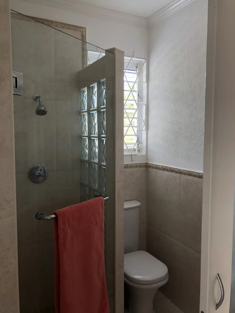 En-suite shower room at 7 Springcourt with walk-in shower, glass block window and tiled walls.