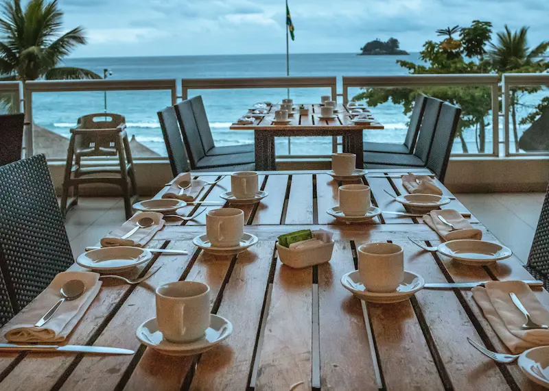 Oceanfront restaurant terrace set for a meal with the Barbados sea just beyond the railing.