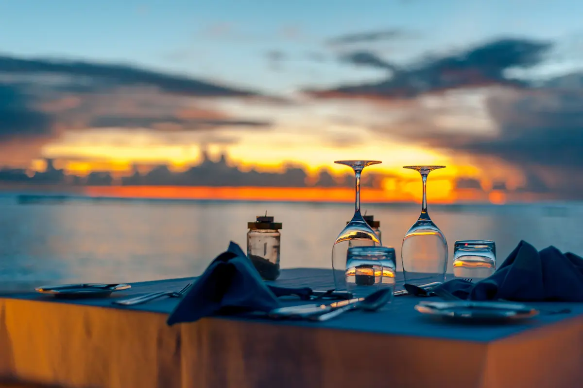 Restaurant table set for dinner at sunset by the water in St Lawrence Gap, Barbados.