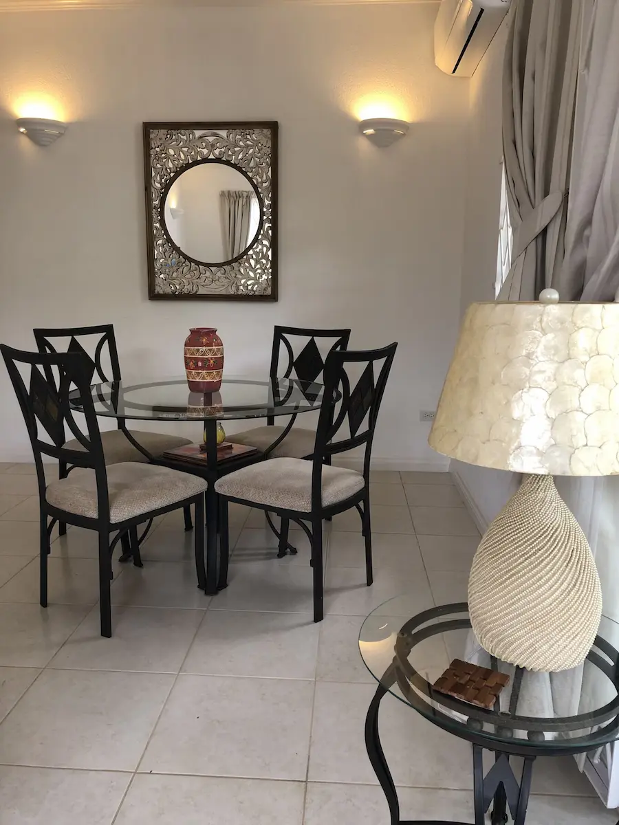 Indoor dining area at 7 Springcourt with round glass table, four chairs and decorative mirror.